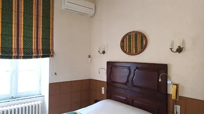 a bedroom with a wooden bed and a window at Hotel Montsegur in Carcassonne