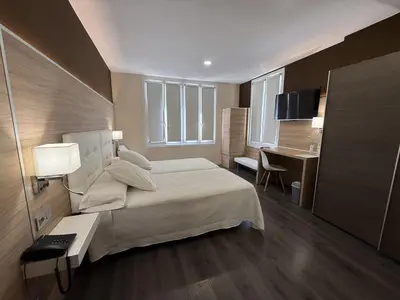 a hotel room with a bed and a desk and a desk at Hotel Restaurant Rose des Pyrénées in Belvianes-et-Cavirac
