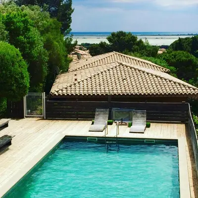 a swimming pool with two chairs and a house at La Poussada, maisons écologiques avec vue mer in Lapalme