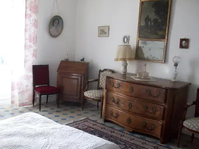 a bedroom with a dresser and a bed and chairs at Le Domaine Du Chapitre in Carcassonne