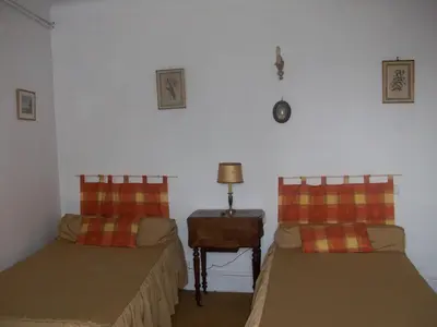 a bedroom with two beds and a table with a lamp at Le Domaine Du Chapitre in Carcassonne