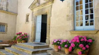 a building with flowers in front of a door at Château de Puichéric in Puicheric
