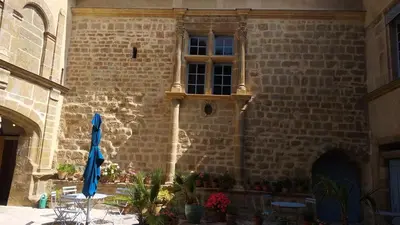 a brick building with a table and a blue umbrella at Château de Puichéric in Puicheric