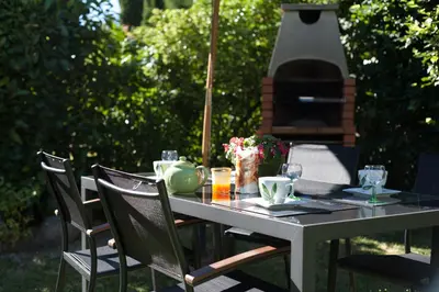 a table with chairs and a grill in a yard at La Prade des 