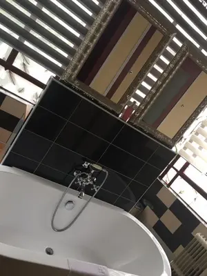 a bathroom with a white sink and black tiles at GUESTHOUSE La VILLAE in Mazamet