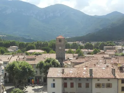 a town with a clock tower with mountains in the background at Entre l'église et la place in Quillan