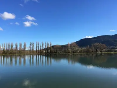 a large lake with trees and mountains in the background at Entre l'église et la place in Quillan