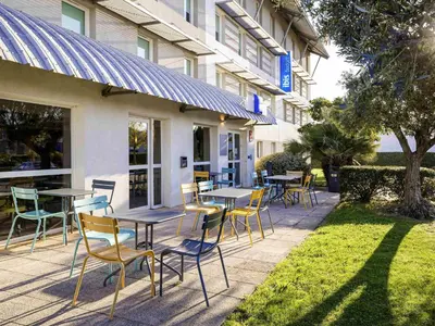 a living room with two chairs and a refrigerator at ibis budget Carcassonne Aéroport - A61 in Carcassonne