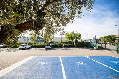 a tennis court with two cars parked in a parking lot at ibis budget Carcassonne Aéroport - A61 in Carcassonne