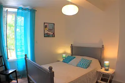 a bedroom with a bed with blue curtains and a window at Gite La Luciole in Tourtrol