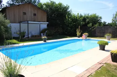 a swimming pool in a backyard with a barn at Gite La Luciole in Tourtrol
