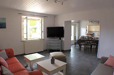 a living room with a couch and a dining room at Gite La Luciole in Tourtrol