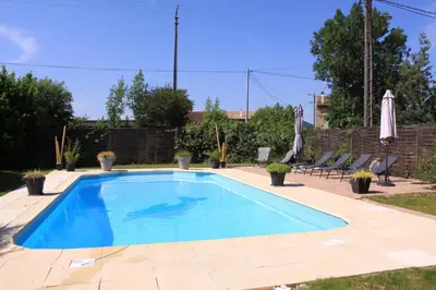 a swimming pool in a yard with chairs and an umbrella at Gite La Luciole in Tourtrol