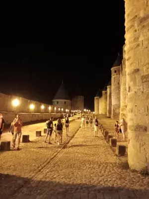 a group of people walking down a street at night at Hotel Astoria in Carcassonne