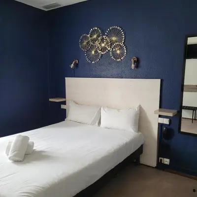 a bedroom with a white bed with blue walls at Hotel Astoria in Carcassonne