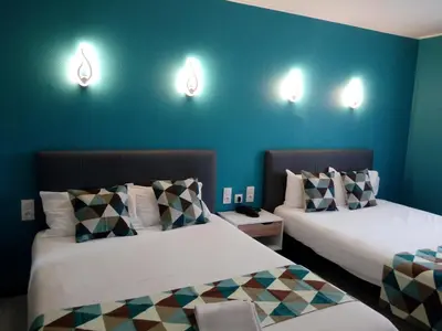 two beds in a room with blue walls and lights at Hotel Astoria in Carcassonne