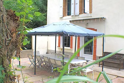 a table and chairs under an umbrella on a patio at Chambres d'hôtes La Luciole in Tourtrol
