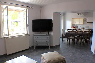 a living room with a television and a dining room at Chambres d'hôtes La Luciole in Tourtrol