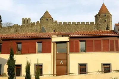 a building with a castle in the background at Adonis Carcassonne in Carcassonne