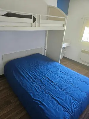 a bunk bed with a blue bedsheet in a room at Hotel Class'Eco Carcassonne in Carcassonne
