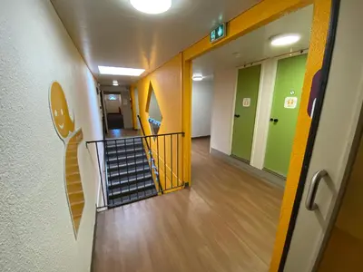 a hallway with a staircase in a hospital with green and yellow walls at Hotel Class'Eco Carcassonne in Carcassonne