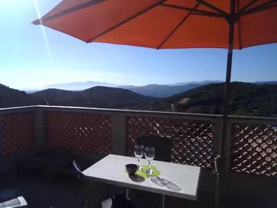 a table with two wine glasses and an umbrella at Chez Pierre in Bélesta