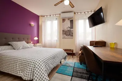 a bedroom with a bed and a desk with a computer at hotel de la paix in Pamiers