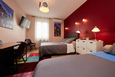 a bedroom with two beds and a desk and a table at hotel de la paix in Pamiers