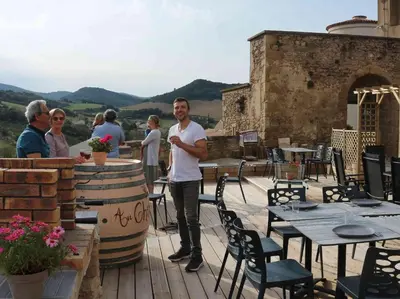 a man standing on a patio with tables and chairs at Au Château de Villelongue B&B in Villelongue-dʼAude
