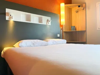 a bedroom with a white bed and a blue wall at ibis budget Carcassonne La Cité in Carcassonne