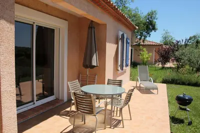 a patio with a table and chairs and an umbrella at Lou Daro in Cébazan
