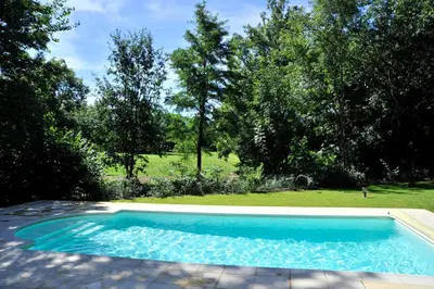 a blue swimming pool in a yard with trees at Lagrange Vacances - Royal Green in Pont-de-Larn
