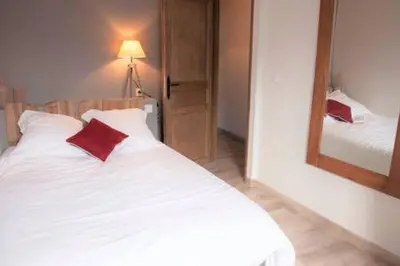 a white bed with red pillows and a mirror at Le Leon d'or in Mirepoix