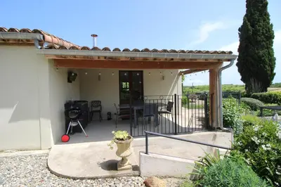 a patio of a house with a table and chairs at Le Petit Cinq in Brézilhac