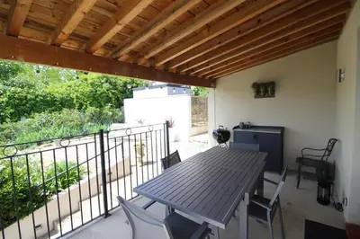 a porch with a wooden table and chairs on a balcony at Le Petit Cinq in Brézilhac