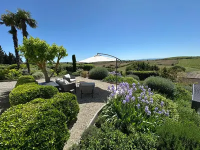 a garden with bushes and purple flowers and trees at Le Petit Cinq in Brézilhac