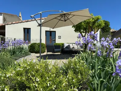 a patio with an umbrella and purple flowers at Le Petit Cinq in Brézilhac
