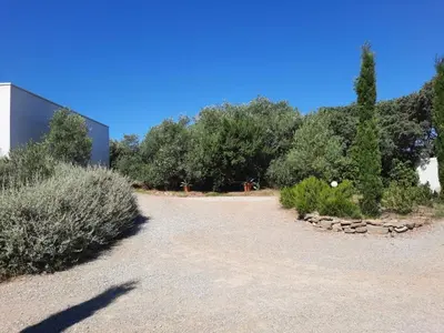 a gravel driveway with bushes and trees in the background at location Phoebé dans la propriété Elaia in Tourouzelle