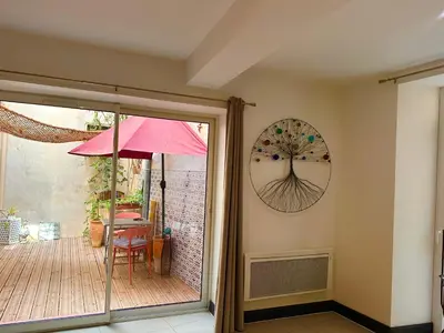 a patio with a red umbrella and some plants at ART'APPART in Narbonne
