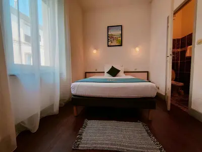 a bedroom with a bed and a window and a rug at Will's Hotel in Narbonne