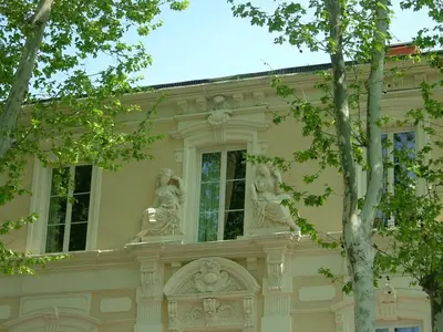 a building with two statues on the side of it at Will's Hotel in Narbonne