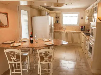 a kitchen with a table with chairs and a refrigerator at Chic Narbonne Pool Retreat in Narbonne
