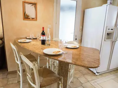 a kitchen with a table with chairs and a refrigerator at Chic Narbonne Pool Retreat in Narbonne