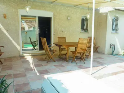 a patio with a wooden table and chairs on a patio at Chic Narbonne Pool Retreat in Narbonne