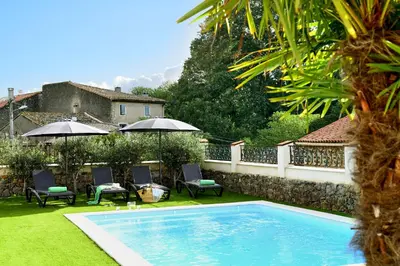 a swimming pool in a yard with chairs and umbrellas at LOFT - Powered by LIEU - in Villedaigne