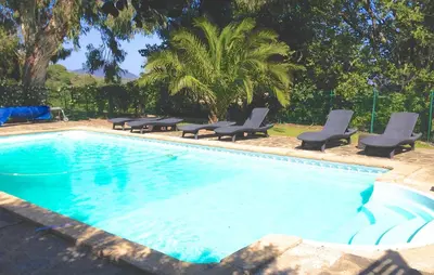 a swimming pool with chaises and chairs next to at Gîte des Orgues d'Ille les Eucalyptus in Ille-sur-Têt
