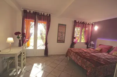 a bedroom with a bed and a desk and windows at Gîte des Orgues d'Ille les Eucalyptus in Ille-sur-Têt