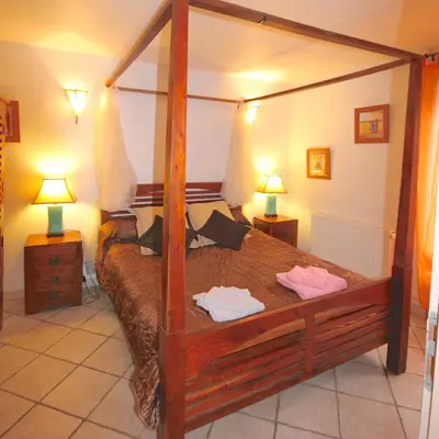 a bedroom with a wooden canopy bed with two lamps at Gîte des Orgues d'Ille les Eucalyptus in Ille-sur-Têt