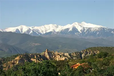 a mountain range with snow capped mountains in the background at Gîte des Orgues d'Ille les Agaves Canigou in Ille-sur-Têt