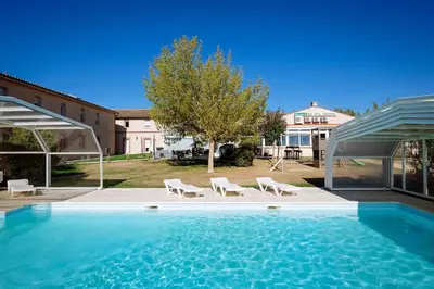 a large swimming pool with chairs and a house at Logis Hôtel - Auberge du Pastel - Hôtel 3 étoiles et Restaurant in Nailloux